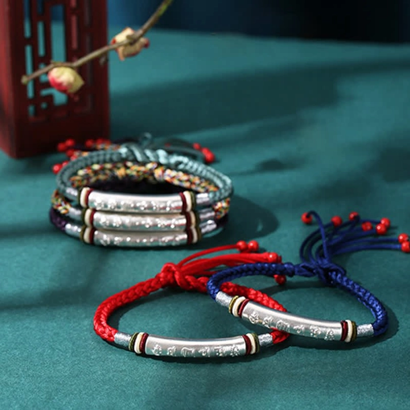 Collection of Om Mani Padme Hum red string bracelets in multiple colors flatlay