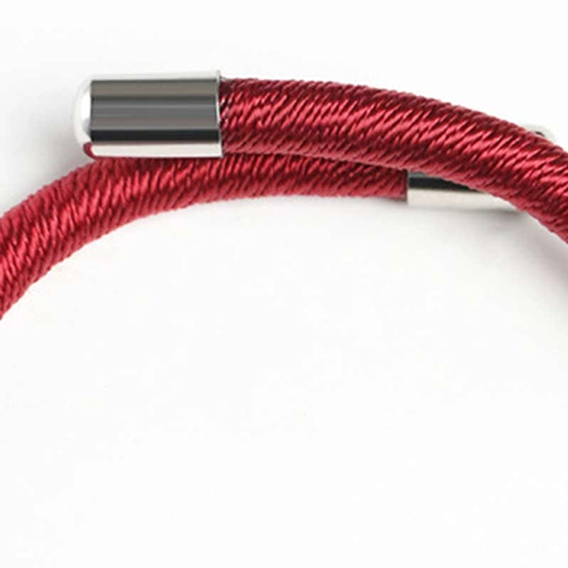 Close-up of Om Mani Padme Hum red string bracelet end detail showing metallic silver caps and braided texture