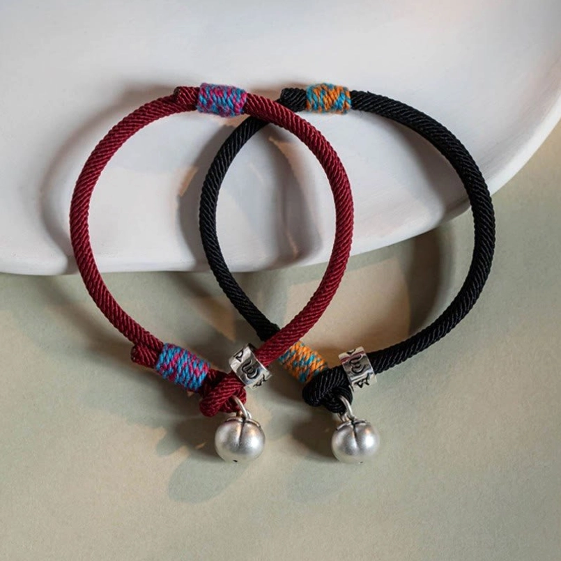 Two Tibetan protection bracelets red and black with silver mantra charms flat lay
