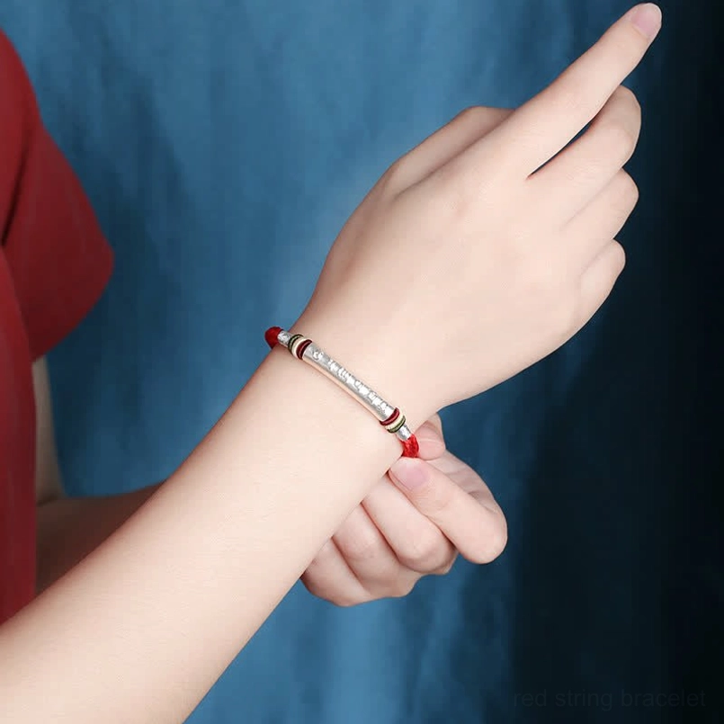 Wearing Om Mani Padme Hum red string bracelet on wrist side view