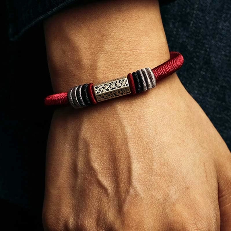 Red cord bracelet with 925 sterling silver Om Mani Padme Hum charm on male wrist
