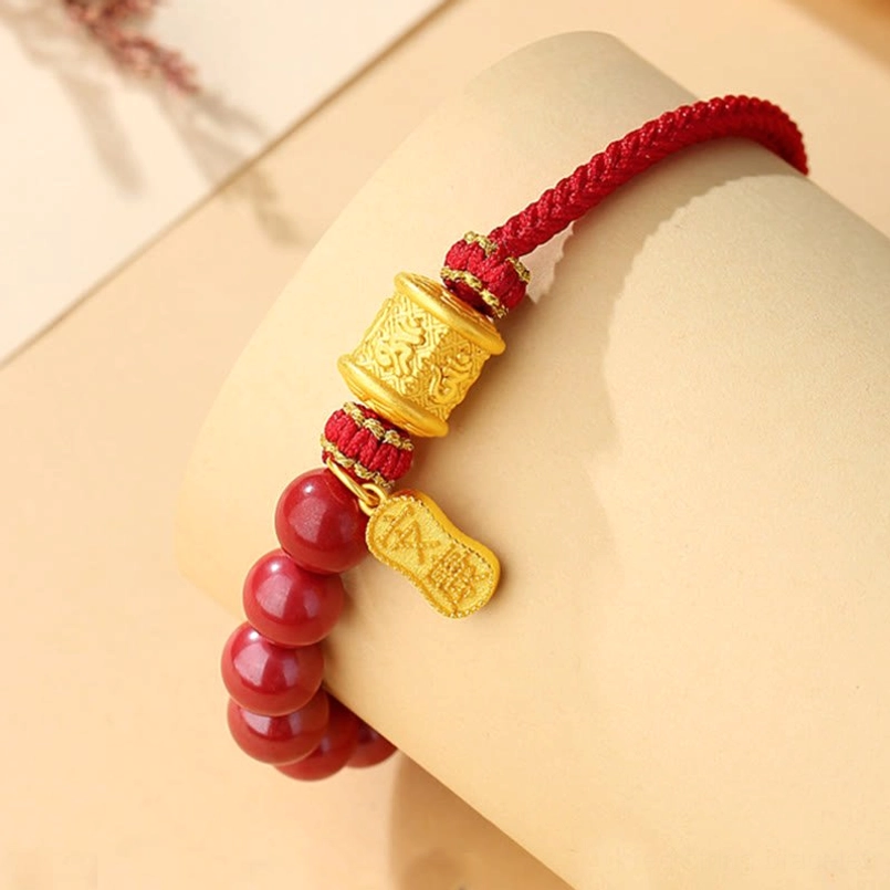 Cinnabar red string bracelet worn on wrist, showing adjustable fit and engraved silver charm details
