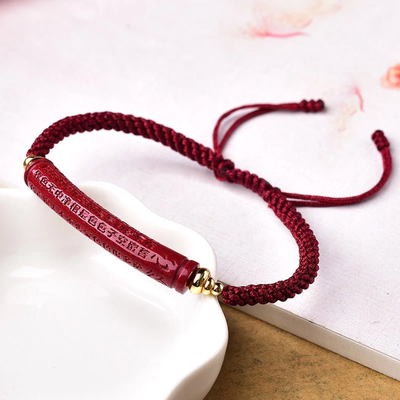 Om Mani Padme Hum engraved cinnabar red string bracelet on white ceramic tray