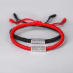 Couple Tibetan Om Mani Padme Hum red and black string bracelets with engraved silver mantra beads flat lay