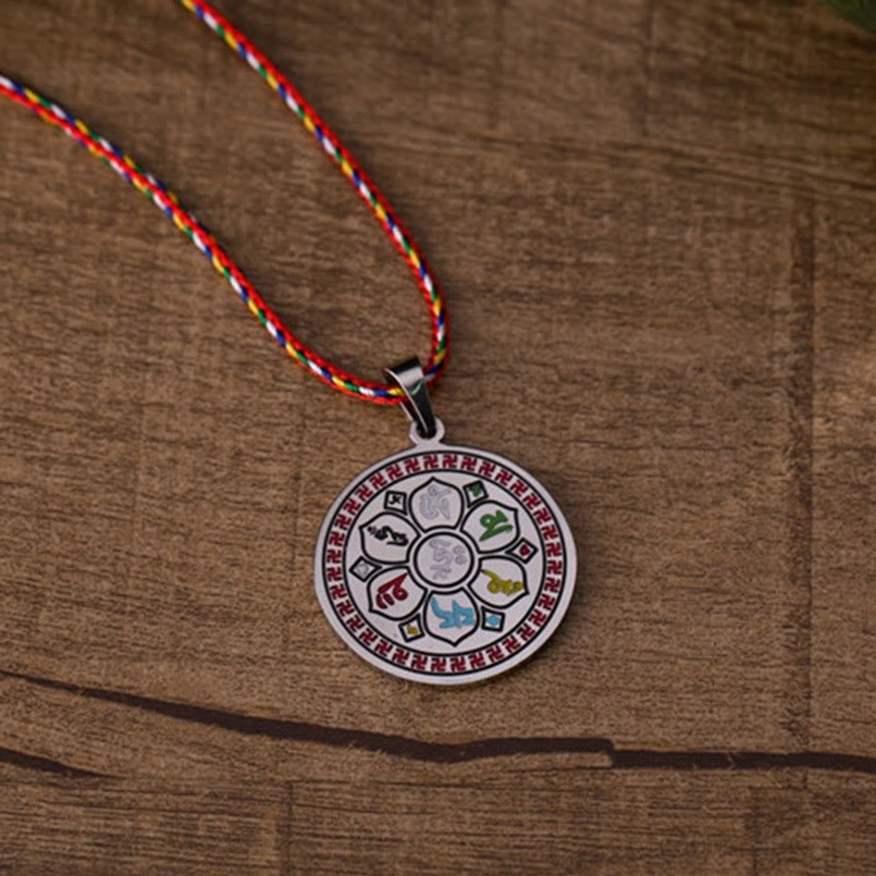 Om Mani Padme Hum silver pendant with multicolor braided rope, flat lay on wood