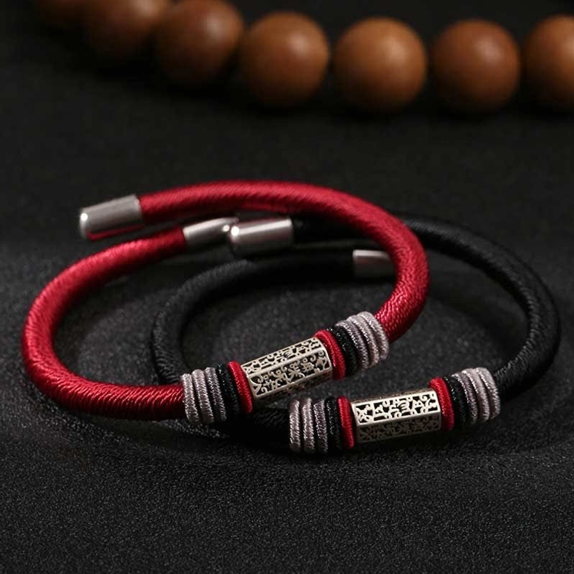 Two Om Mani Padme Hum red string bracelets with silver engraved charm details, artistic composition