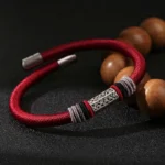Red Om Mani Padme Hum string bracelet with 925 sterling silver engraved charm, overhead view with wooden mala beads
