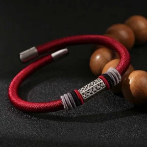Red Om Mani Padme Hum string bracelet with 925 sterling silver engraved charm, overhead view with wooden mala beads