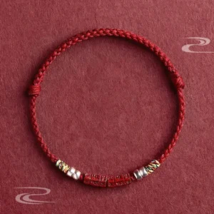 Om Mani Padme Hum red string bracelet with carved cinnabar bead and sterling silver accents, flat lay top view