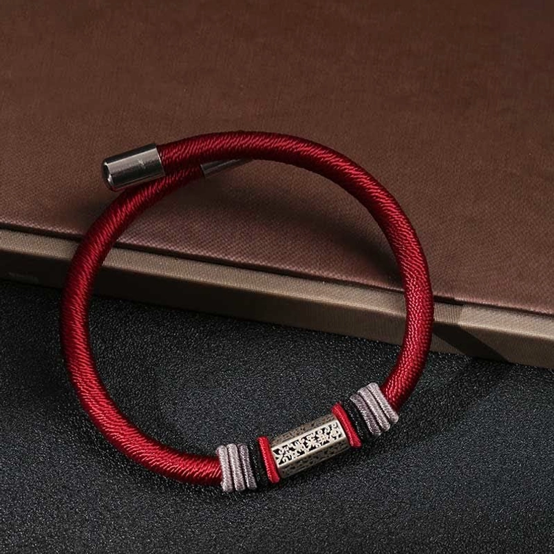 Red braided cord Om Mani Padme Hum bracelet with silver engraved center piece, flat overhead shot