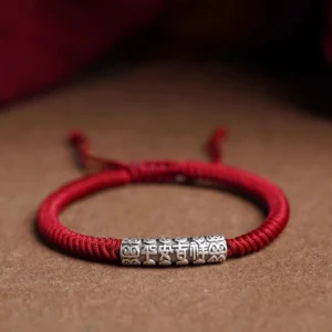 Om Mani Padme Hum sterling silver red string bracelet with engraved silver bead on brown background