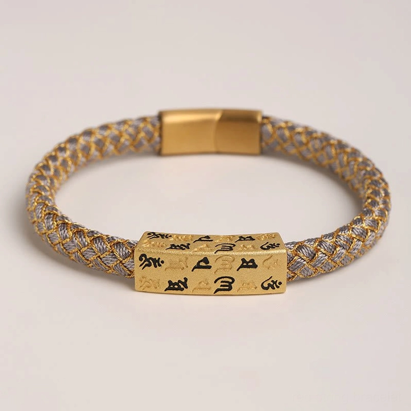 Flat lay view of gray Om Mani Padme Hum Tibetan bracelet with gold threading and rectangular mantra charm