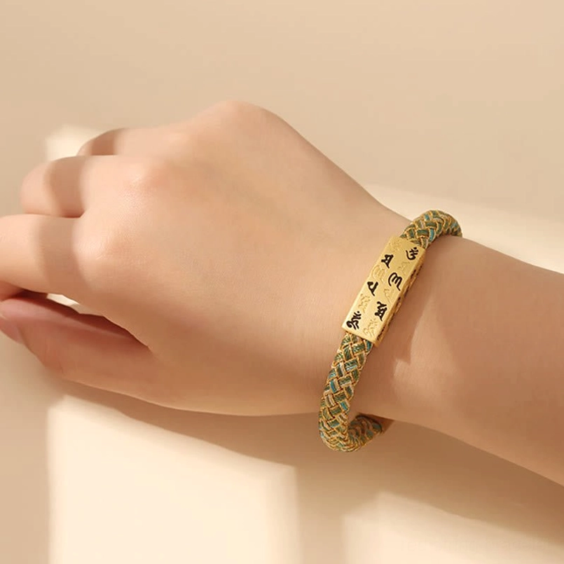 Three-quarter view of red Om Mani Padme Hum Tibetan bracelet with gold thread and sacred mantra charm