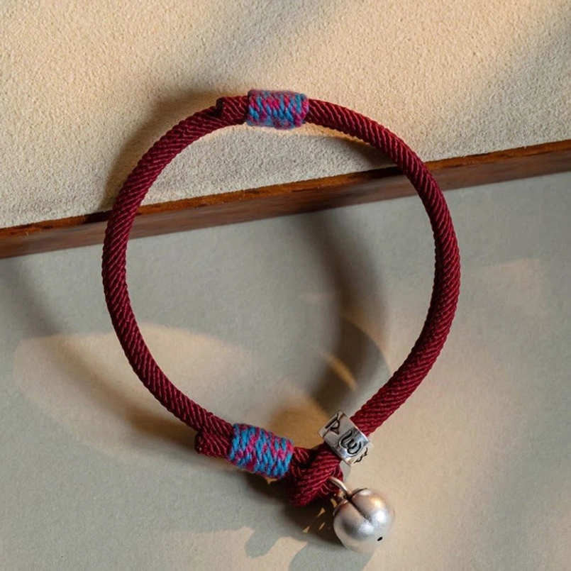 Wine red Tibetan braided bracelet with silver persimmon charm on velvet display