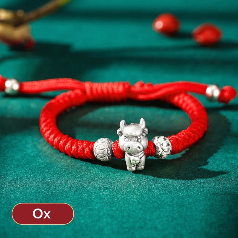 Ox Chinese zodiac 999 sterling silver red braided rope bracelet flat lay with gemstones background