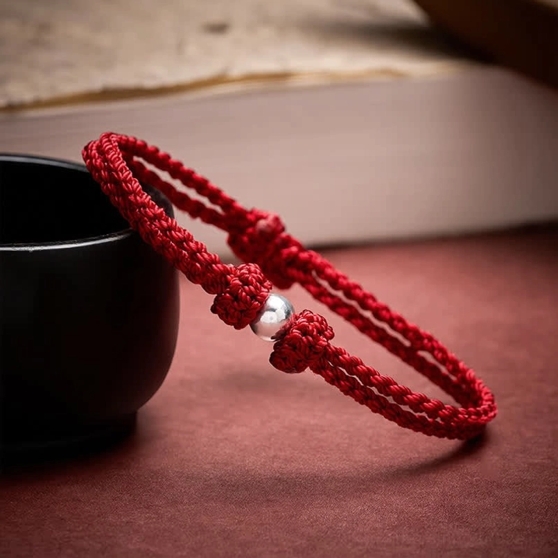 Two matching red string bracelets with 925 silver beads displayed on tabletop
