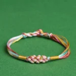 Pastel rainbow braided red string bracelet with pink peach blossom knot front view