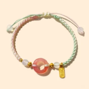 Peace buckle agate red string bracelet with gold charm, dual-tone woven cord, top-down view