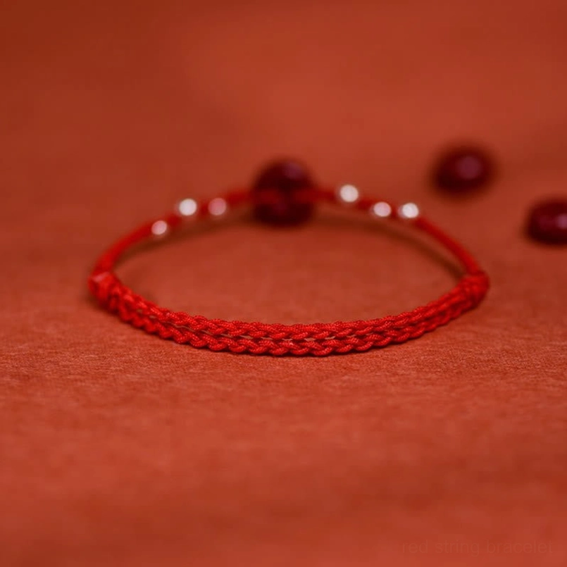 Cinnabar peace buckle bracelet front flat view with loose cinnabar beads and woven cord