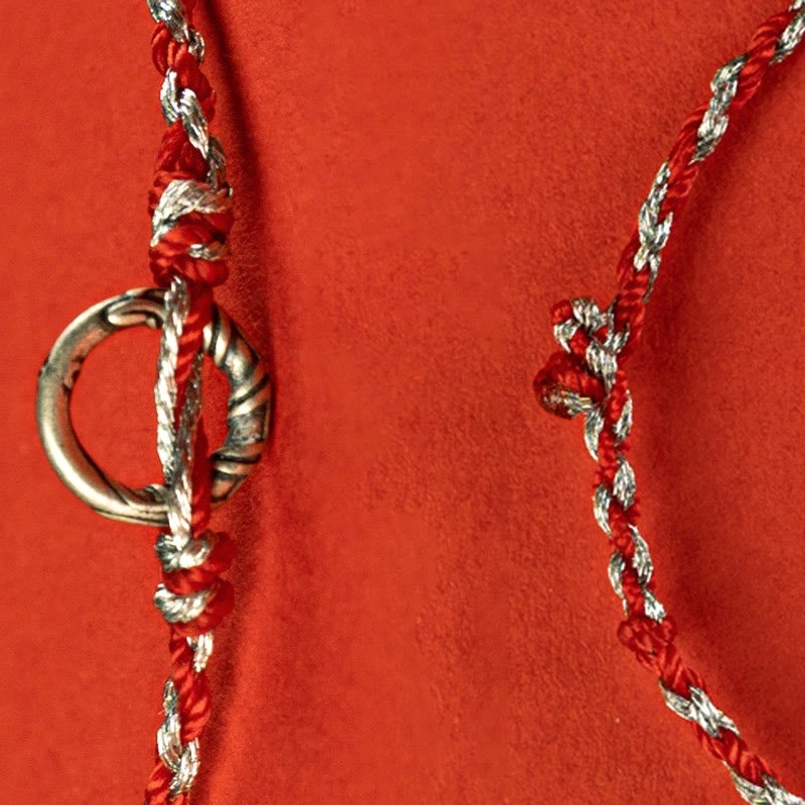 Bracelet detail close-up showing twisted braid texture and silver peace buckle
