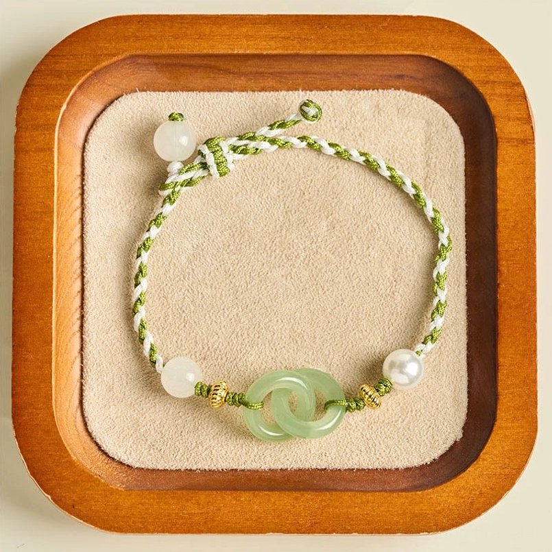 Green braided peace buckle bracelet staged on wooden velvet jewelry display tray
