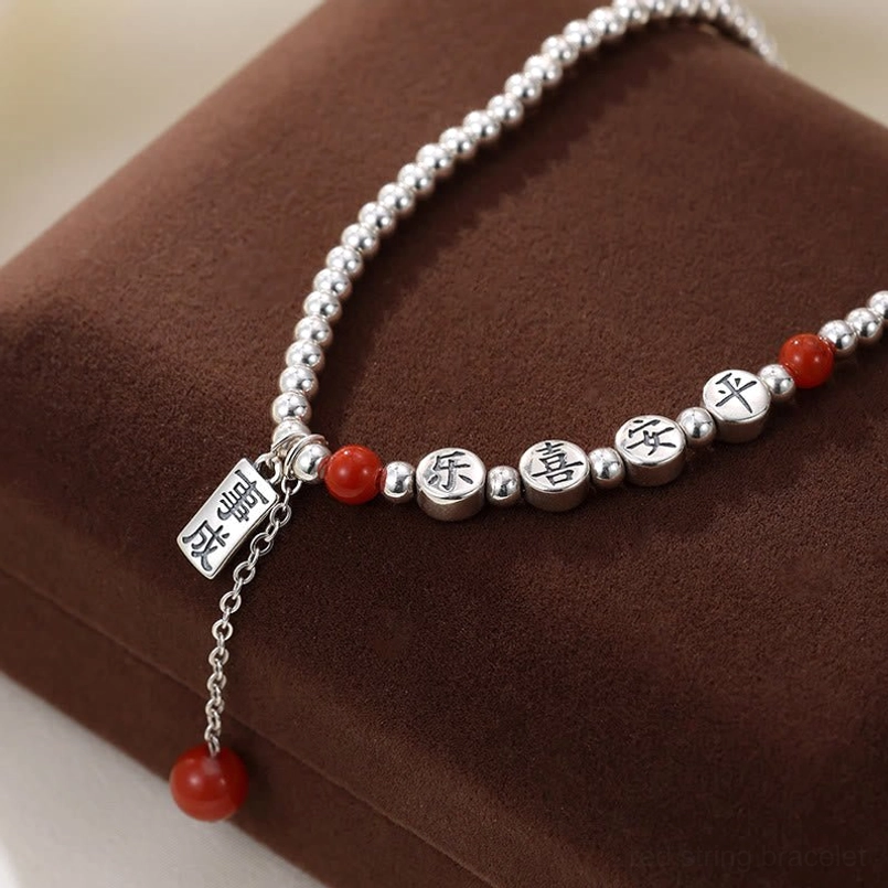 Sterling silver peace and joy blessing anklet with dangling success charm on brown display surface