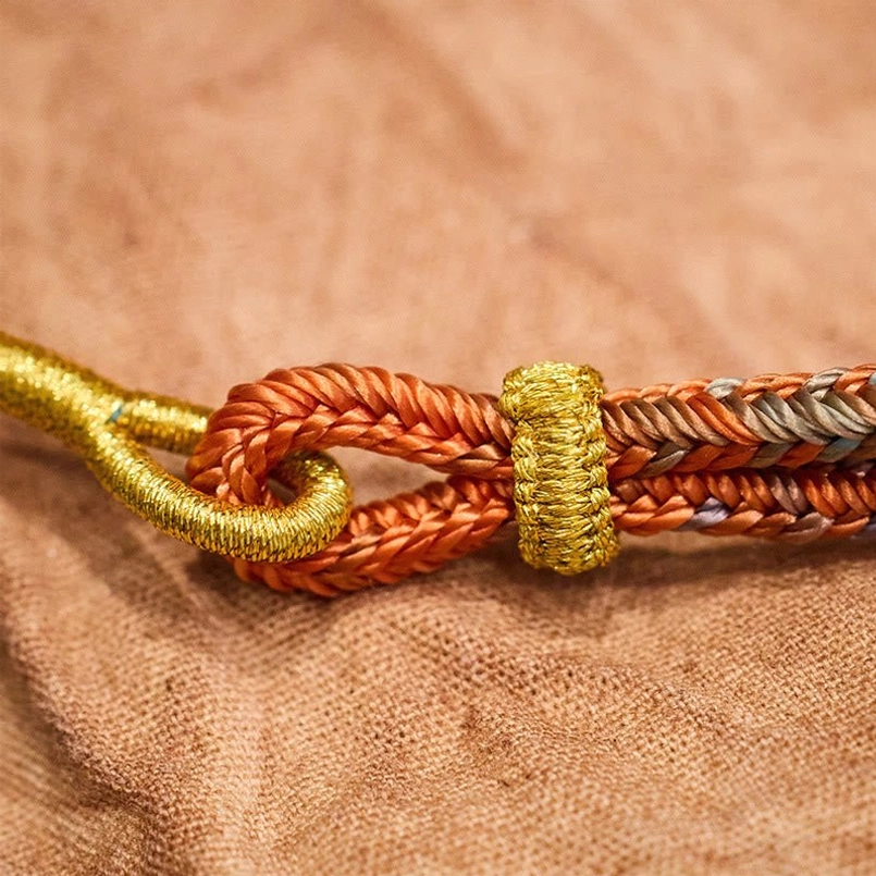 Hand-tied knot detail of handcrafted peace knot bracelet showing twisted orange rope