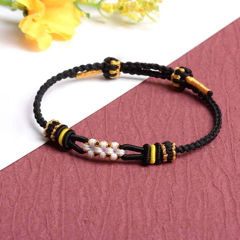 Black woven peach blossom luck bracelet with gold and yellow accent knots white flower center decoration
