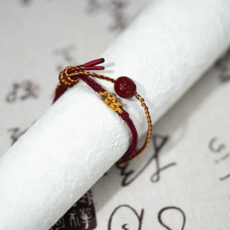 Double-strand braided blessing bracelet with gold decorative knot on Chinese calligraphy background