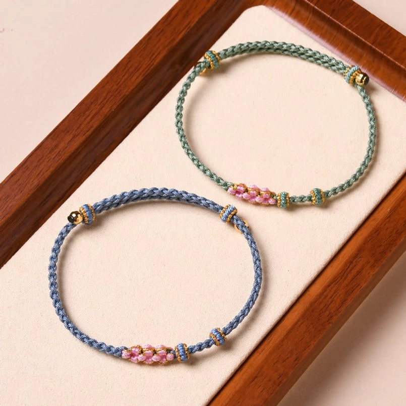 Red string bracelet with peach blossom charms close-up detail of gold hardware