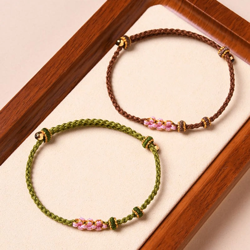 Handmade red string peach blossom bracelet on wrist showing adjustable fit