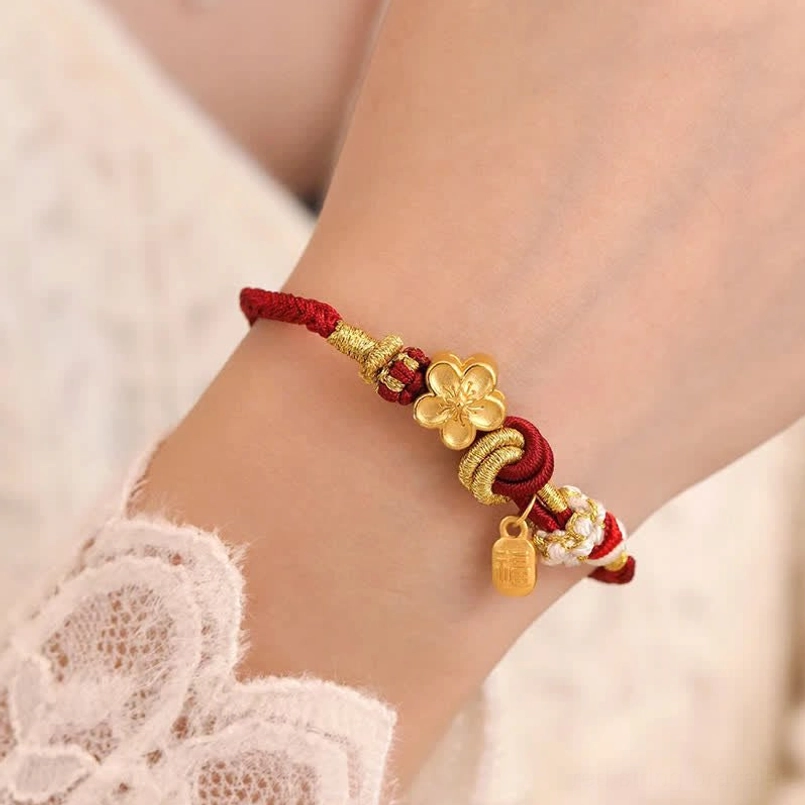 Detailed close-up of peach blossom red string bracelet with gold charm and beaded accents