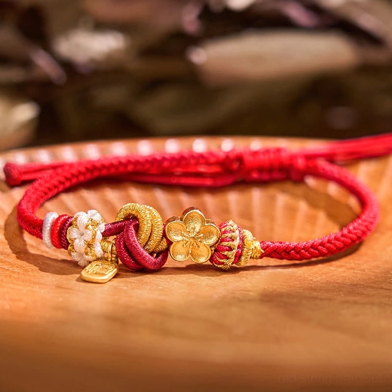 Flat lay overhead view of lucky peach blossom red string bracelet with foliage background
