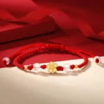 Peach blossom red string bracelet with gold charm and pink chalcedony beads on festive red gift background