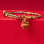 Peach wood Fu character red string bracelet high overhead view on red tabletop