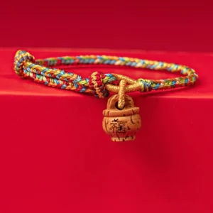Peach wood Fu character red string bracelet high overhead view on red tabletop
