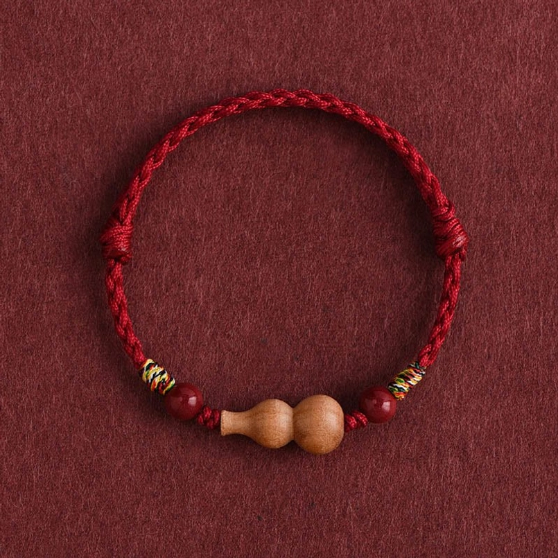 Peach wood gourd red string bracelet with cinnabar beads and colorful woven accents, full top-down view