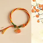 Persimmon red agate reincarnation knot bracelet flat lay with metal charm and tassel detail
