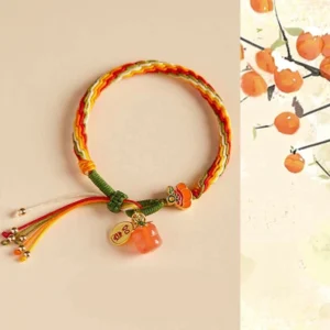 Persimmon red agate reincarnation knot bracelet flat lay with metal charm and tassel detail