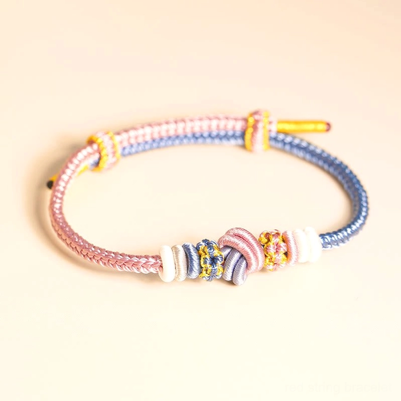 Pink and blue pastel woven peace knot bracelet on light background tabletop display