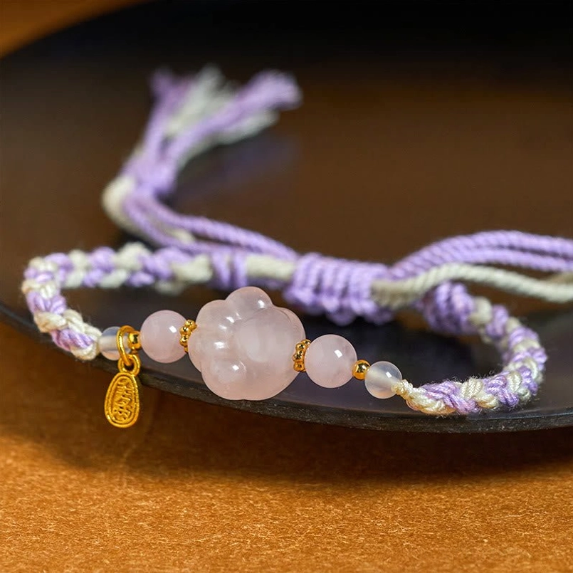 Close up pink crystal cat claw braided bracelet on dark plate