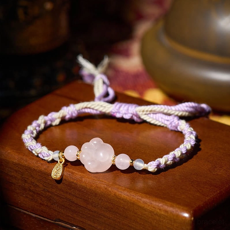 Flat lay pink crystal cat paw string bracelet in dark wooden storage box