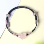 Pink crystal heart bracelet adjustable black cord flat lay view