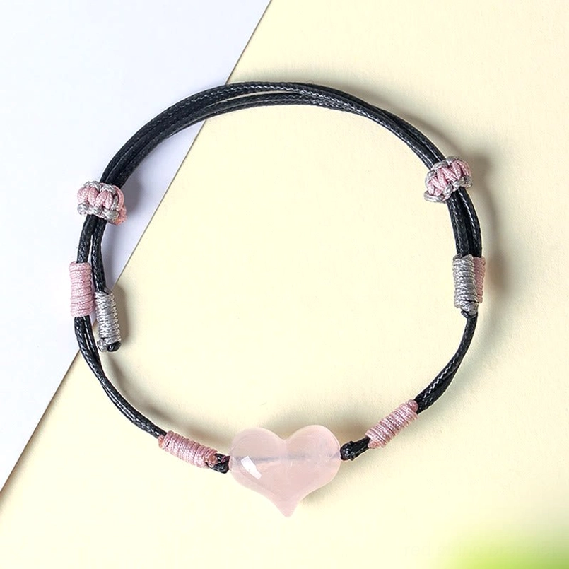 Pink crystal heart bracelet adjustable black cord flat lay view