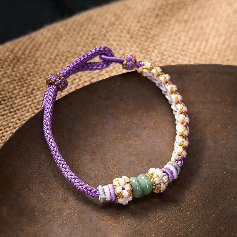 Pink Chinese knot bracelet showing braided pattern and jade accents