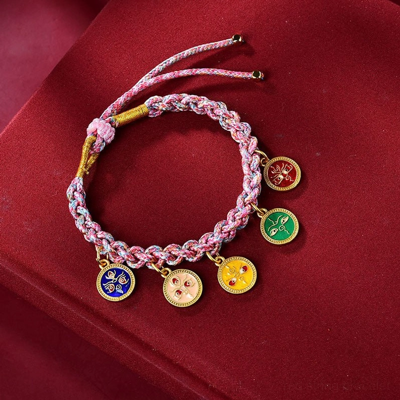 Close up of pink yellow Tibetan braided five gods of wealth bracelet on red velvet