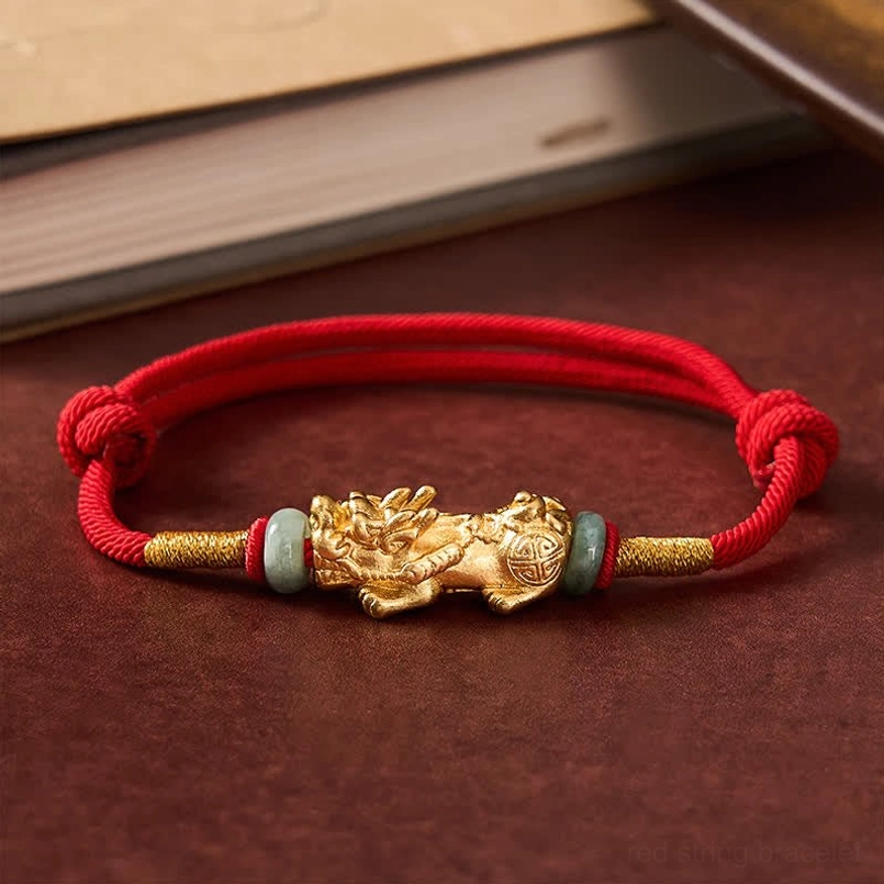 Flat lay top-down view of pi xiu red string bracelet with symmetrical jade spacers and adjustable cord