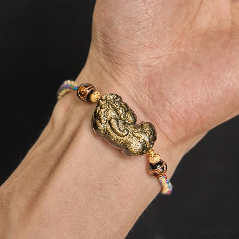 Gold Sheen Obsidian PiXiu bracelet worn on right wrist with earthy braided cord on bare skin