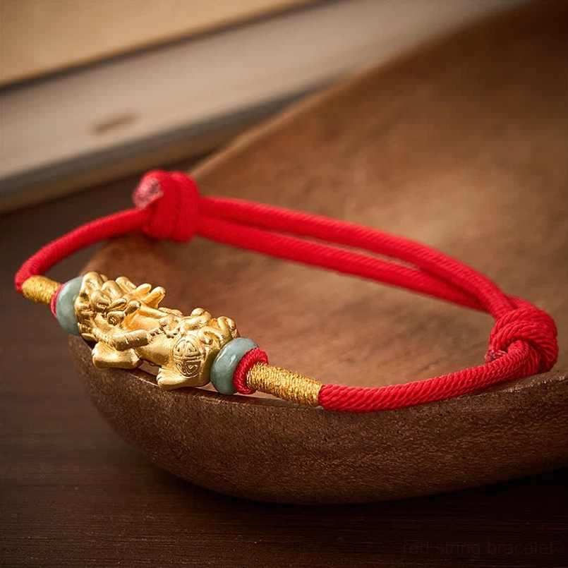 Side angle view of braided red cord adjustable pi xiu bracelet with detailed gold figurine