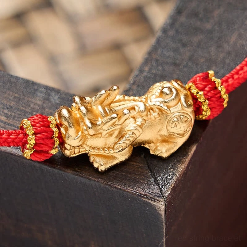 3D carved golden Pixiu talisman detail on red-gold woven knots - top close-up view